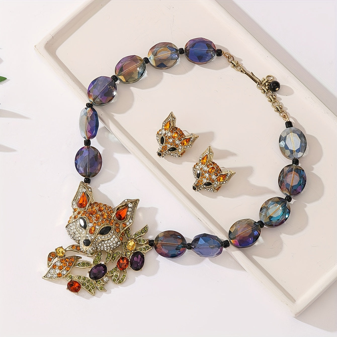 This luxury and exquisitely designed jewelry set features a pendant necklace and earrings adorned with inlaid water diamonds, fox leaves, and colorful acrylic beads. The set is elegant and fashionable, making it the perfect gift for women. It is ideal