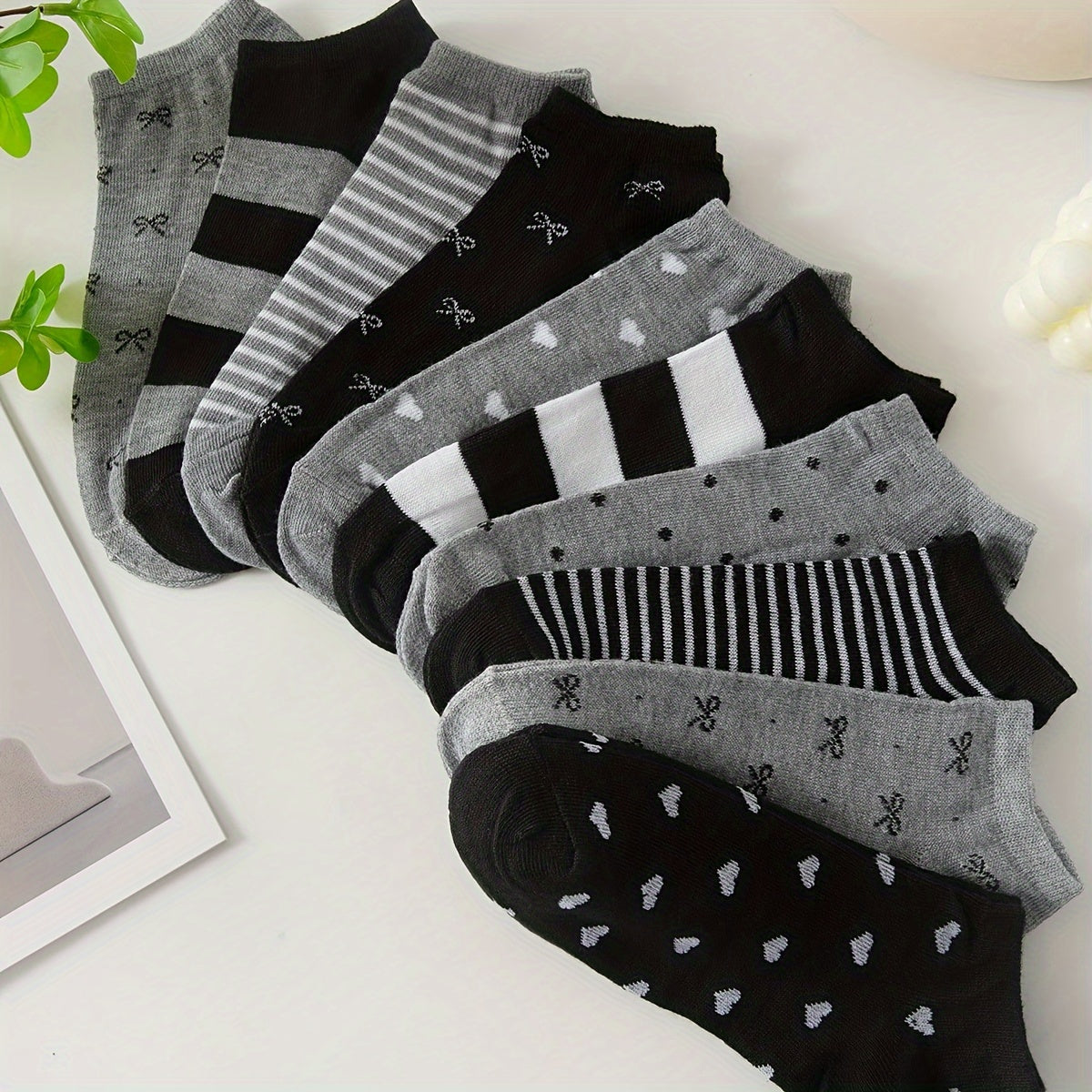 Women's ankle socks in black and grey with assorted geometric patterns. Made from comfortable knit fabric, 95% polyester and 5% spandex. Random style shipping. 10/20 pairs available.