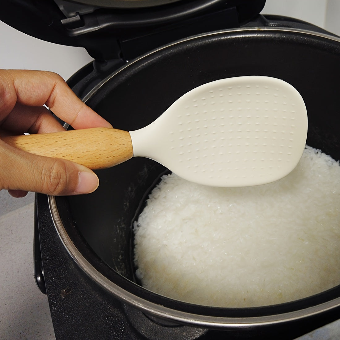 Silicone rice spoon with wooden handle, ideal for non-stick cookware, durable and convenient serving utensil.