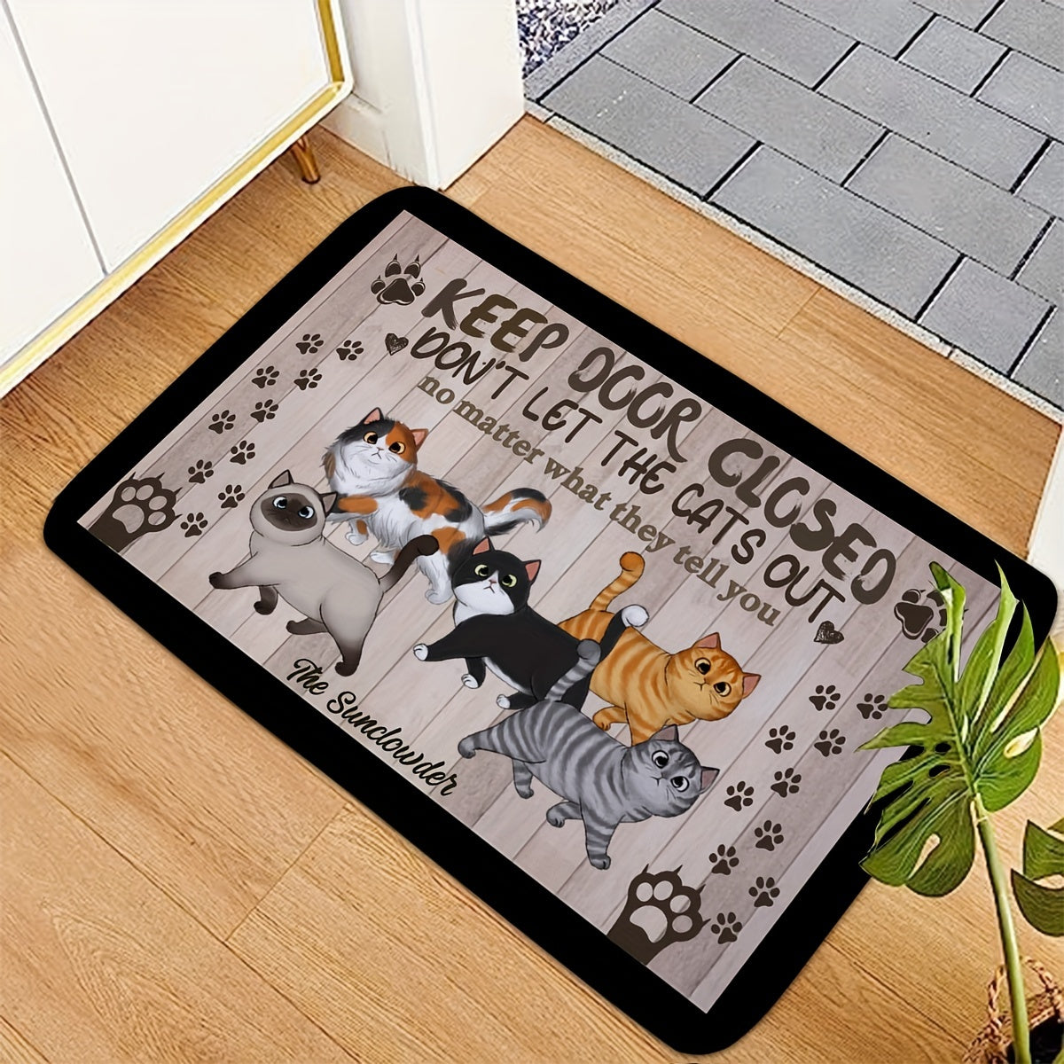 Welcome your guests with this whimsical cat-themed welcome mat featuring cute cartoon cats and paw prints. Made of non-slip, machine washable polyester, this door mat is perfect for both indoor and outdoor use. The black mat is complemented by a wooden