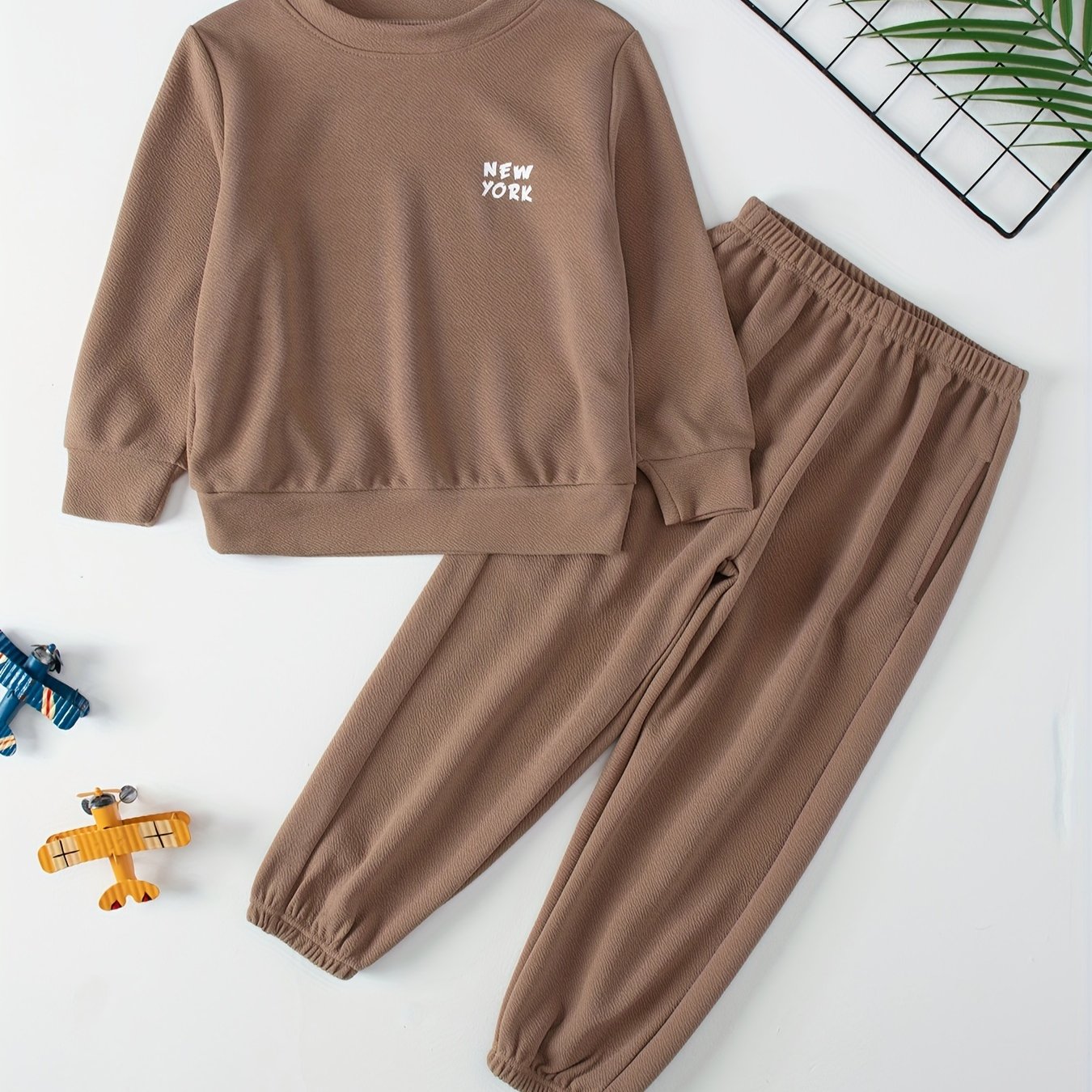 Children's casual sweatshirt and pants set made of polyester and spandex blend. Solid color with round neck, long sleeves, and knit fabric. Regular fit with pocket detail, suitable for