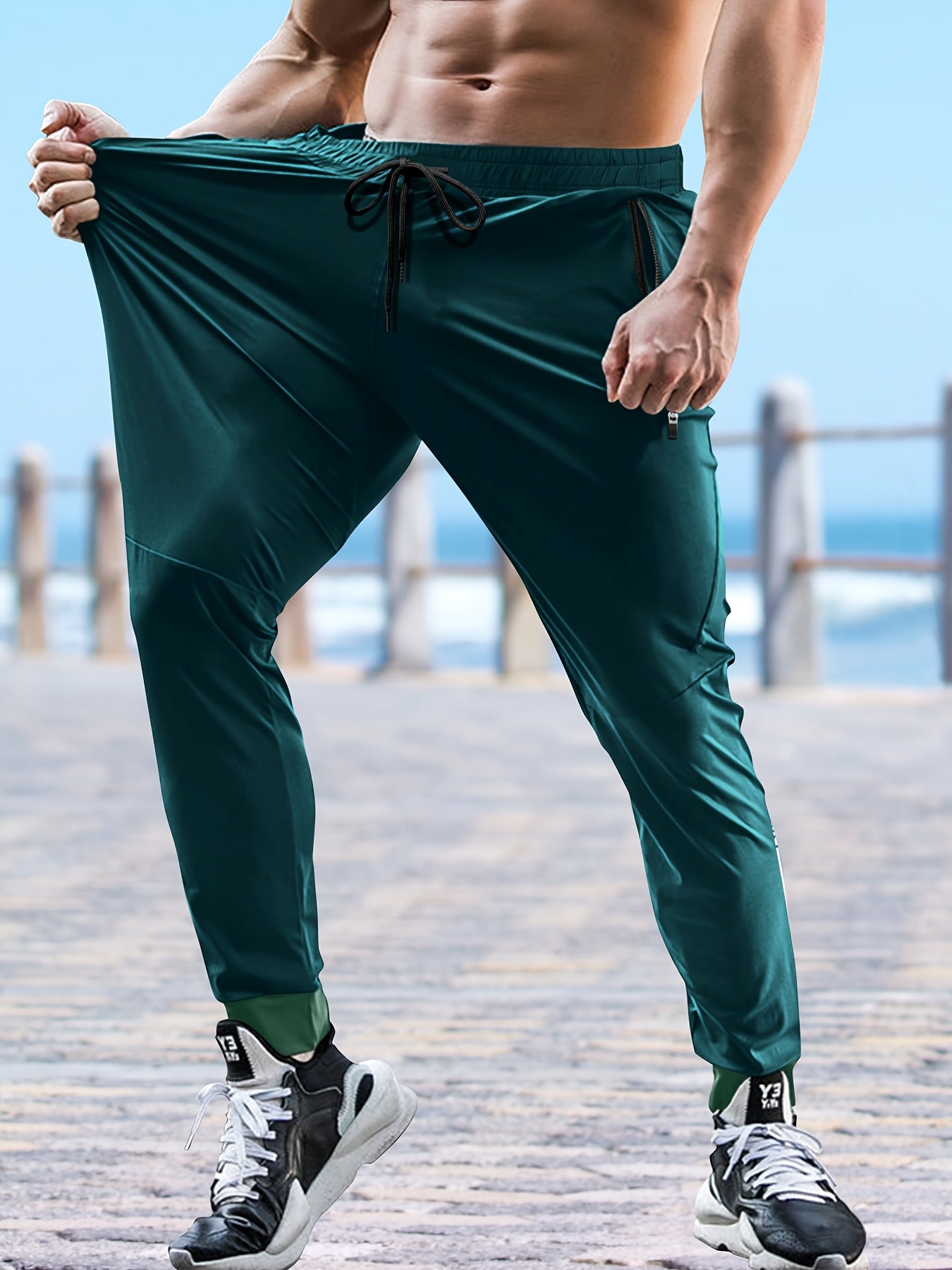 Men's solid color cuffed sports pants made of 100% polyester with moisture-wicking properties. Features a drawstring waist, loose fit, and quick-dry technology for various activities and