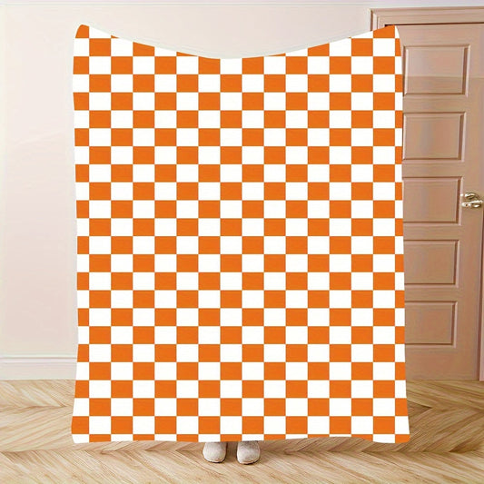 One piece of an orange and white checkered print fleece throw blanket featuring a geometric pattern. This all-season blanket is machine washable, durable, and anti-tear, making it perfect for use in the bedroom, living room, or while camping. It weighs