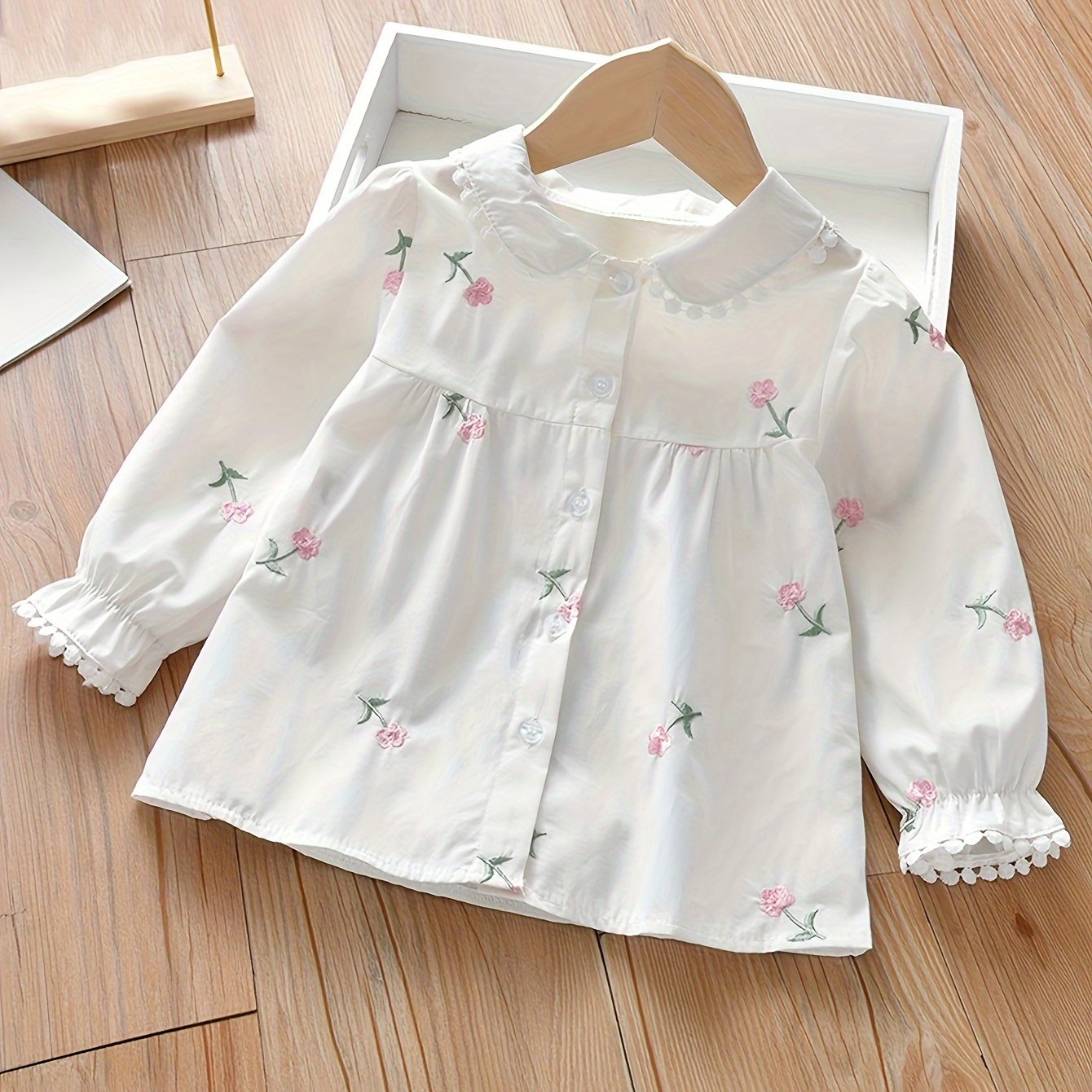 Girls' long-sleeve shirt with embroidered floral design, ideal for spring/fall. Casual and versatile in cotton blend fabric.