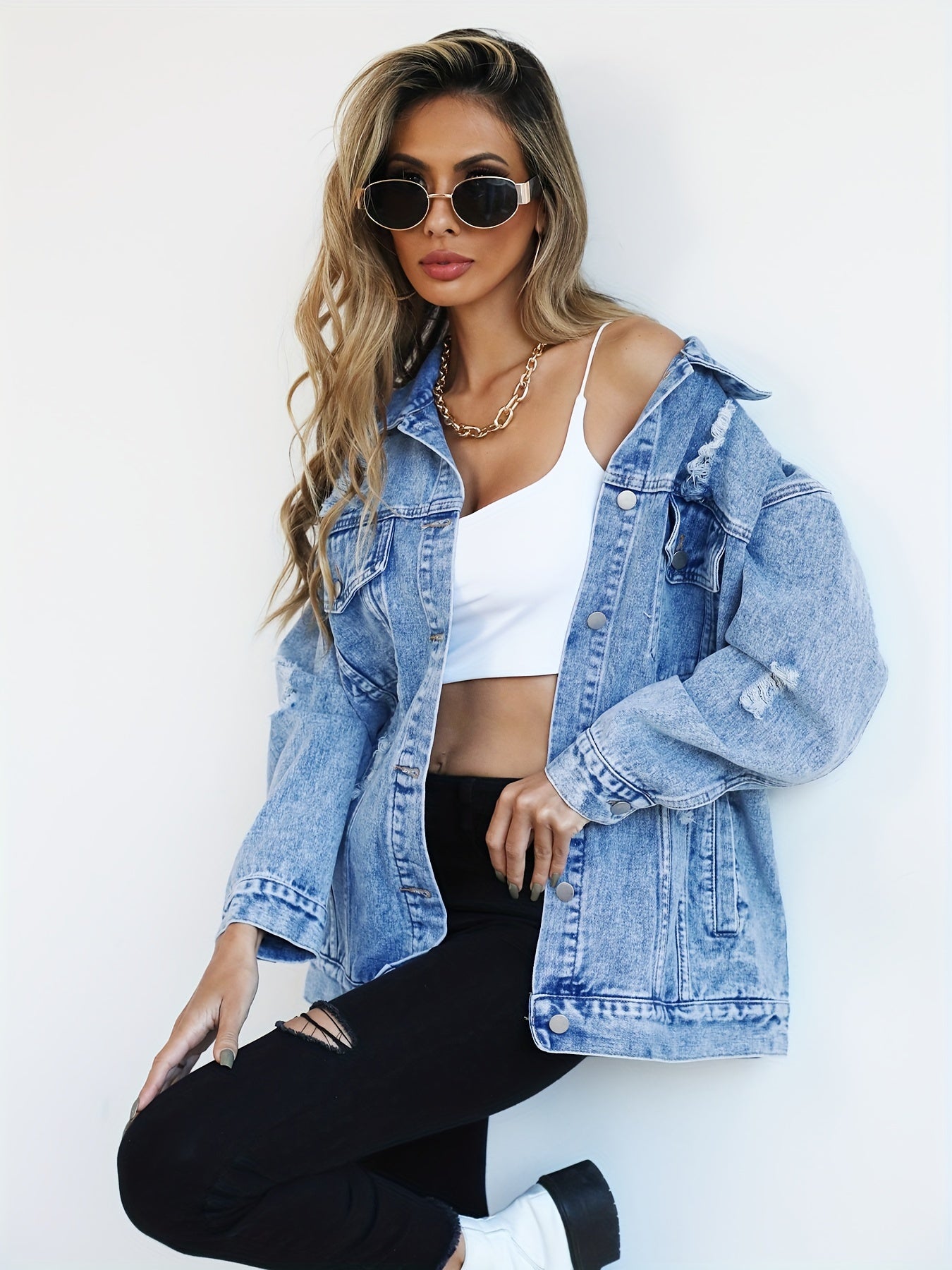 Casual light blue denim jacket for women with distressed, loose fit and ripped detailing, featuring long sleeves, flap pockets, and button closure. Made from a blend fabric and machine