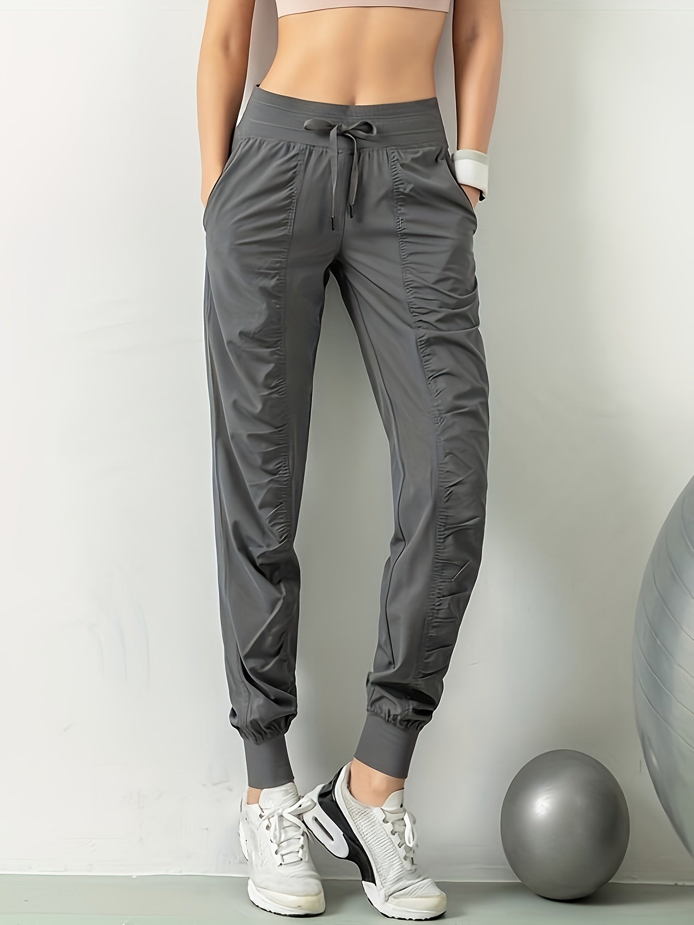 Women's solid color sports pants with drawstring waist, quick drying material, and side pockets for casual comfort.