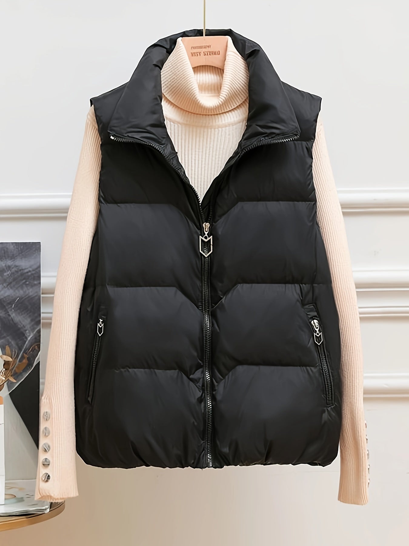 Sleeveless beige duck down vest with side pockets and zip-up closure. Perfect for fall/winter layering with a loose fit and 80g white duck down fill. Made of polyester with a glossy finish.