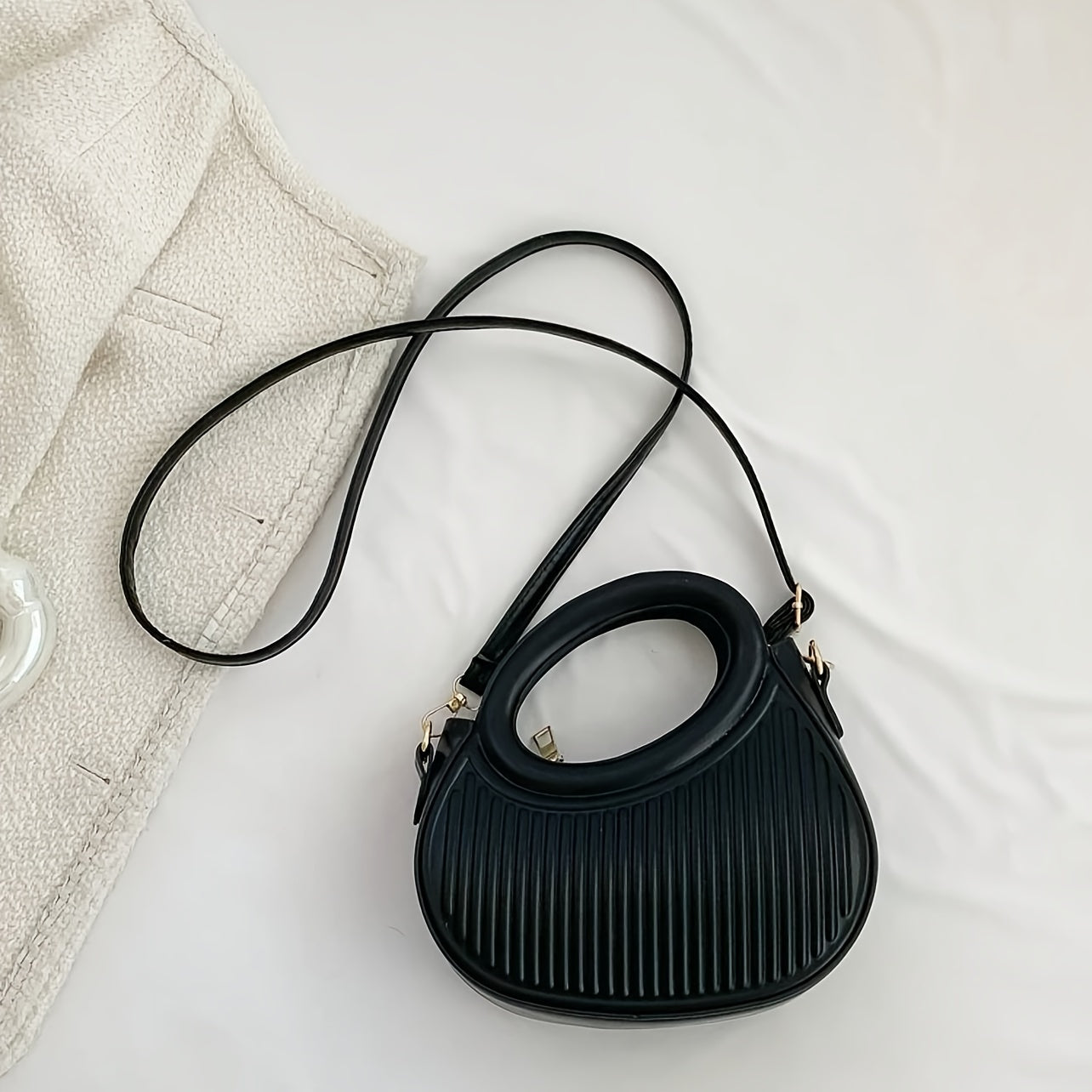 Chic black crossbody bag with embossed stripe pattern and golden-tone hardware, versatile for everyday use with a luxury look.