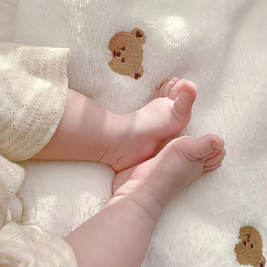 Soft polyester white blanket featuring an embroidered bear design, perfect for cozy youngsters.