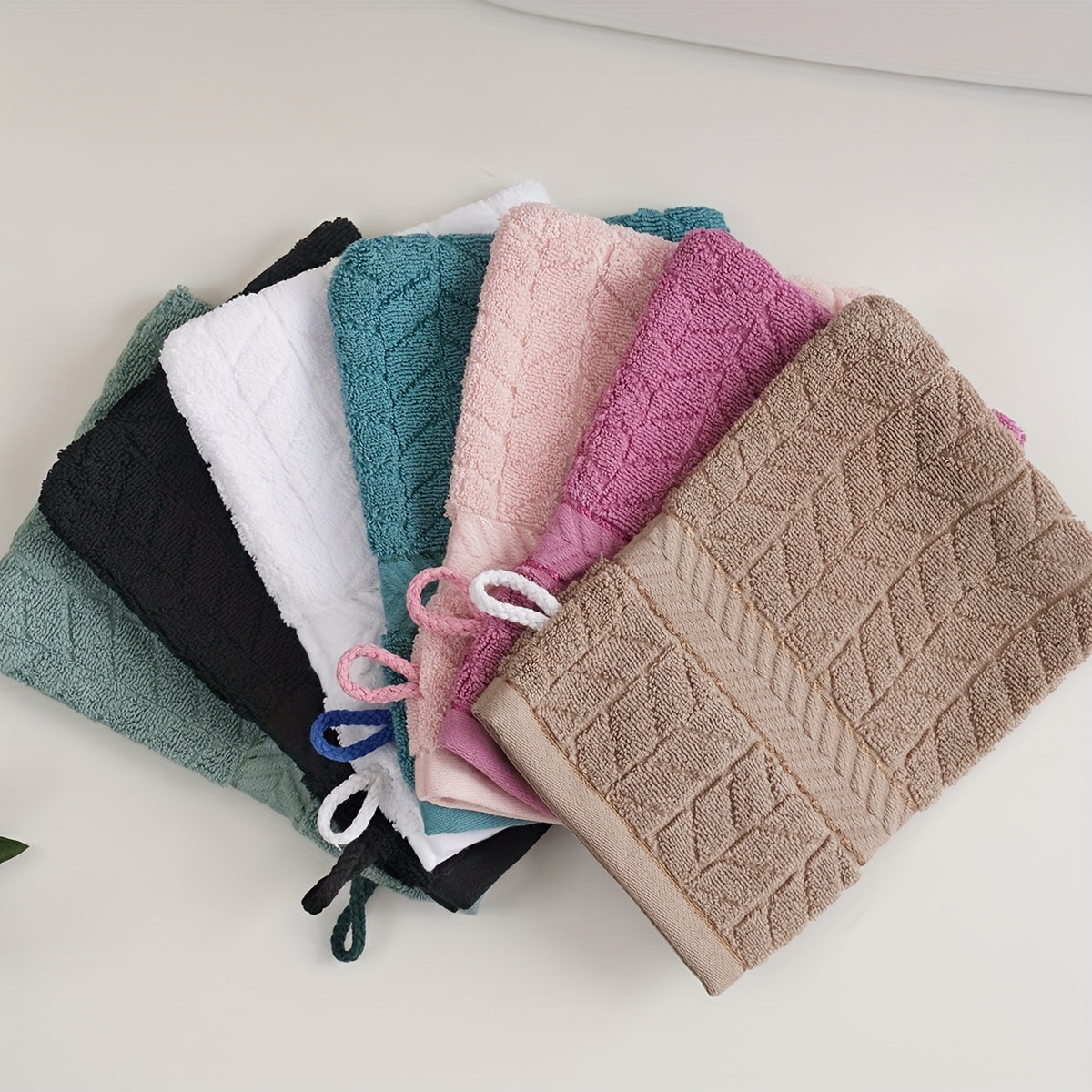 3 soft cotton bath gloves in geometric patterns for makeup removal, available in pink, green, black, white, and teal blue. Ideal for bathing and hand use.