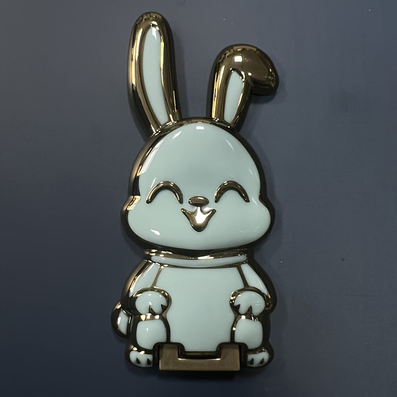 Foldable waterproof phone stand made of ABS material, featuring an adjustable cartoon bunny design for holding smartphones and tablets.