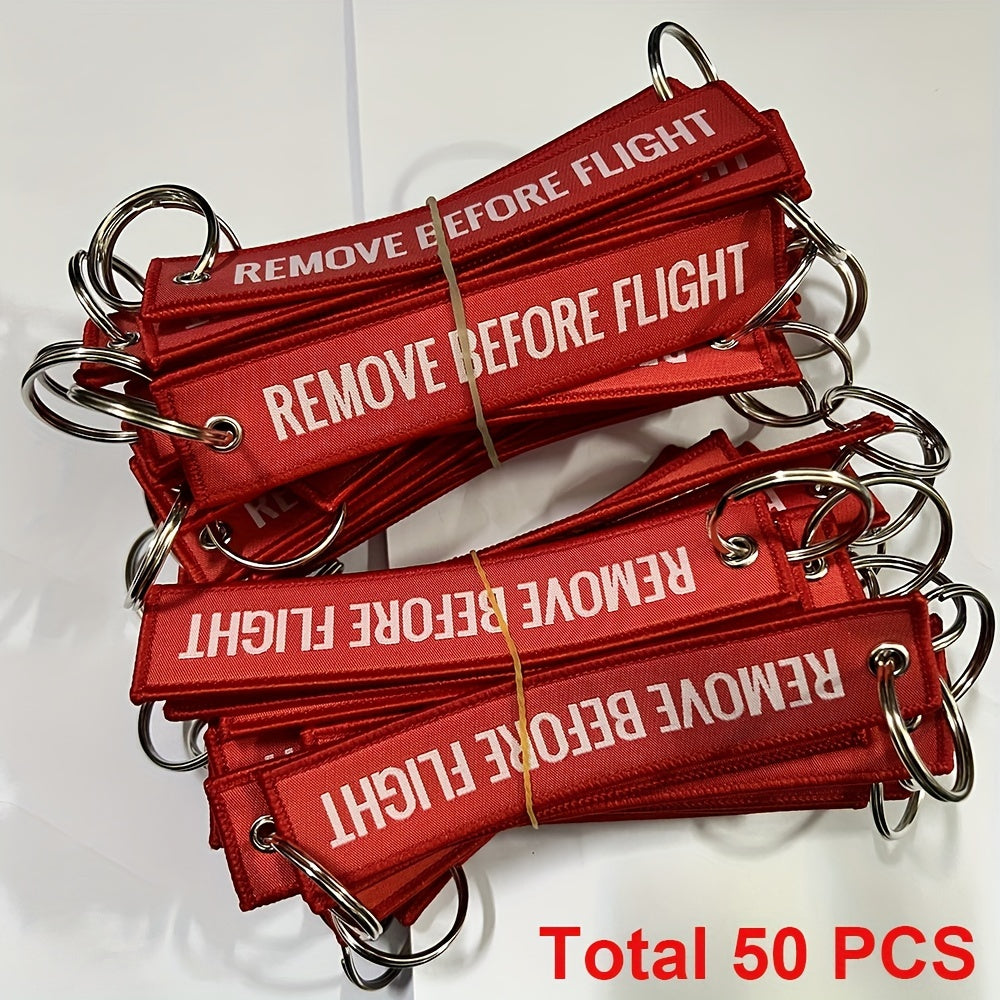 Bundle of 50 'Remove Before Flight' Woven Keychains made from sturdy polyester material - Ideal present for pilots and aviation fans, featuring the iconic phrase "REMOVE BEFORE FLIGHT