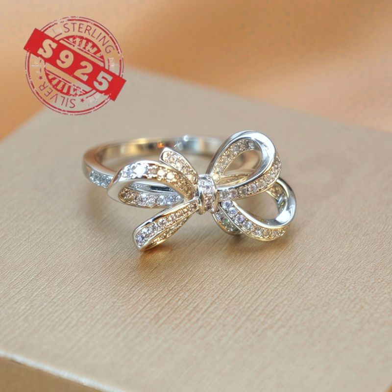 Chic 925 Sterling Silver Ribbon Bow Tie Ring featuring Natural Zirconia, perfect for July Birthdays. This Tribal & Cute style ring is 925 Silver Plated, Tarnish-Resistant, and adorned with Heart-Themed details. Ideal for Daily Wear or Wedding occasions