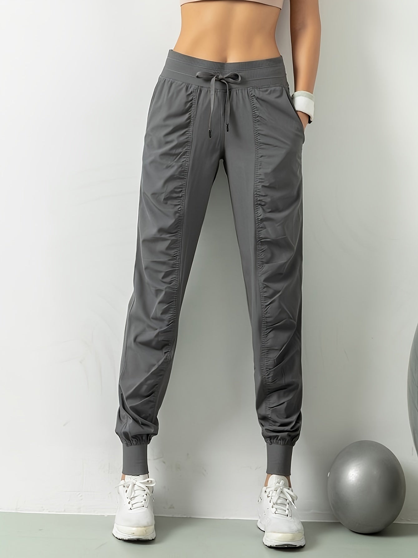 Women's solid color sports pants with drawstring waist, quick drying material, and side pockets for casual comfort.