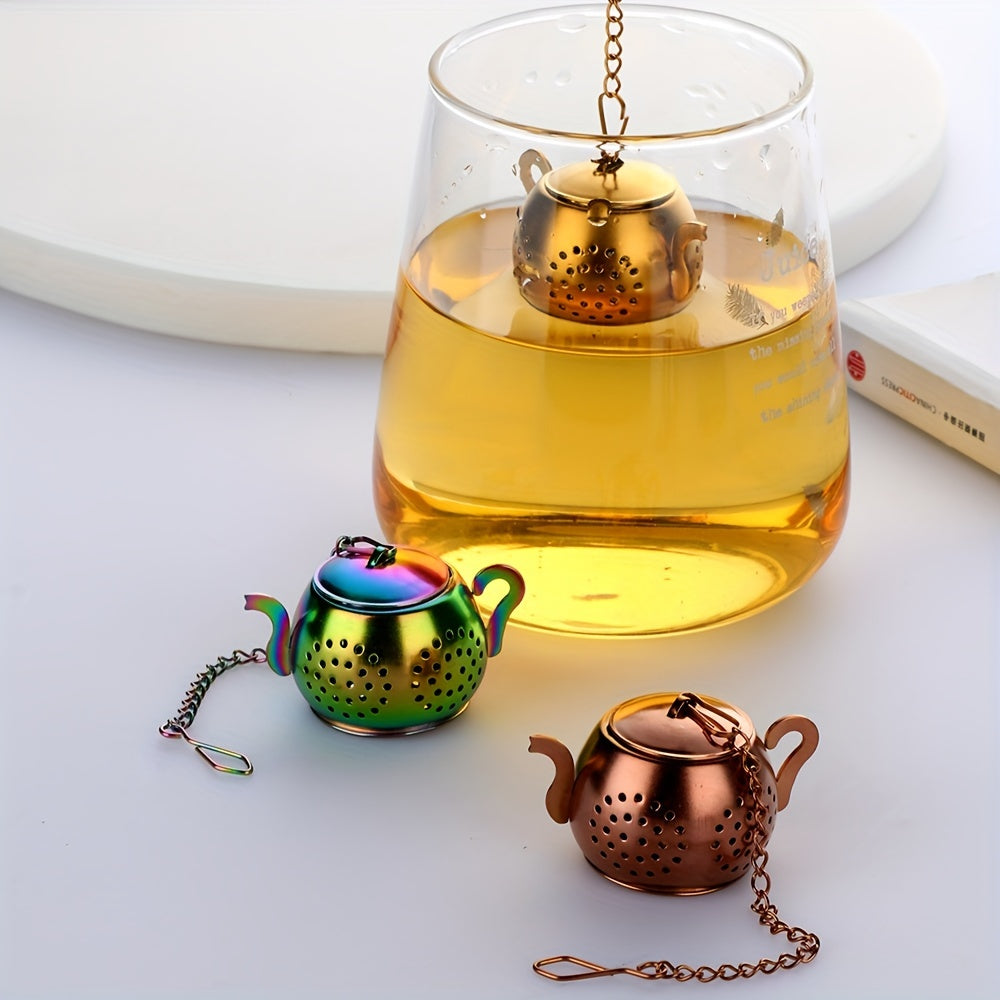 Golden rose stainless steel teapot-shaped tea strainer with uniform filter holes and hanging chain for cups.