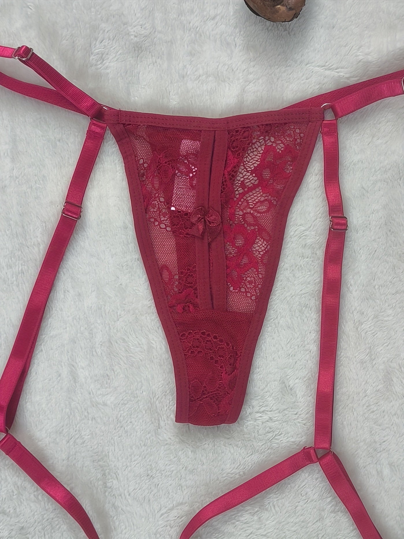 Adult party style G-string with lace contrast, solid color, adjustable straps, and drop waist V-string thong. Made of polyamide and elastane blend knit fabric.