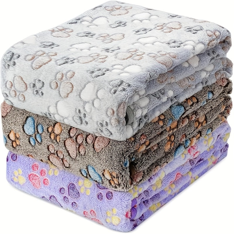 Paw print patterned pet fleece blanket, machine washable and stain resistant, suitable for all dog sizes.