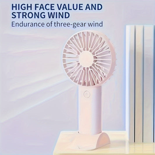 Portable, rechargeable handheld fan with a mobile phone holder - Compact design in white, blue, or pink colors. Ideal for use on desks or outdoors, this high-speed mini fan includes a USB charging cable for convenience. Perfect for staying cool on the go.