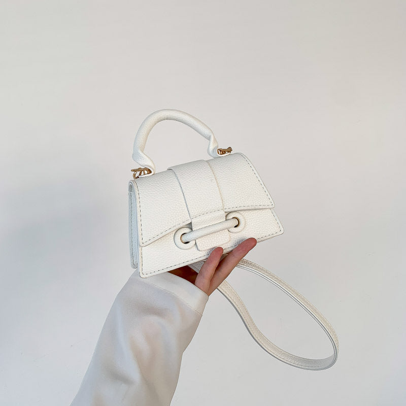 Girl's trendy mini crossbody bag in a solid color with a top handle, perfect for lipstick and other small essentials.