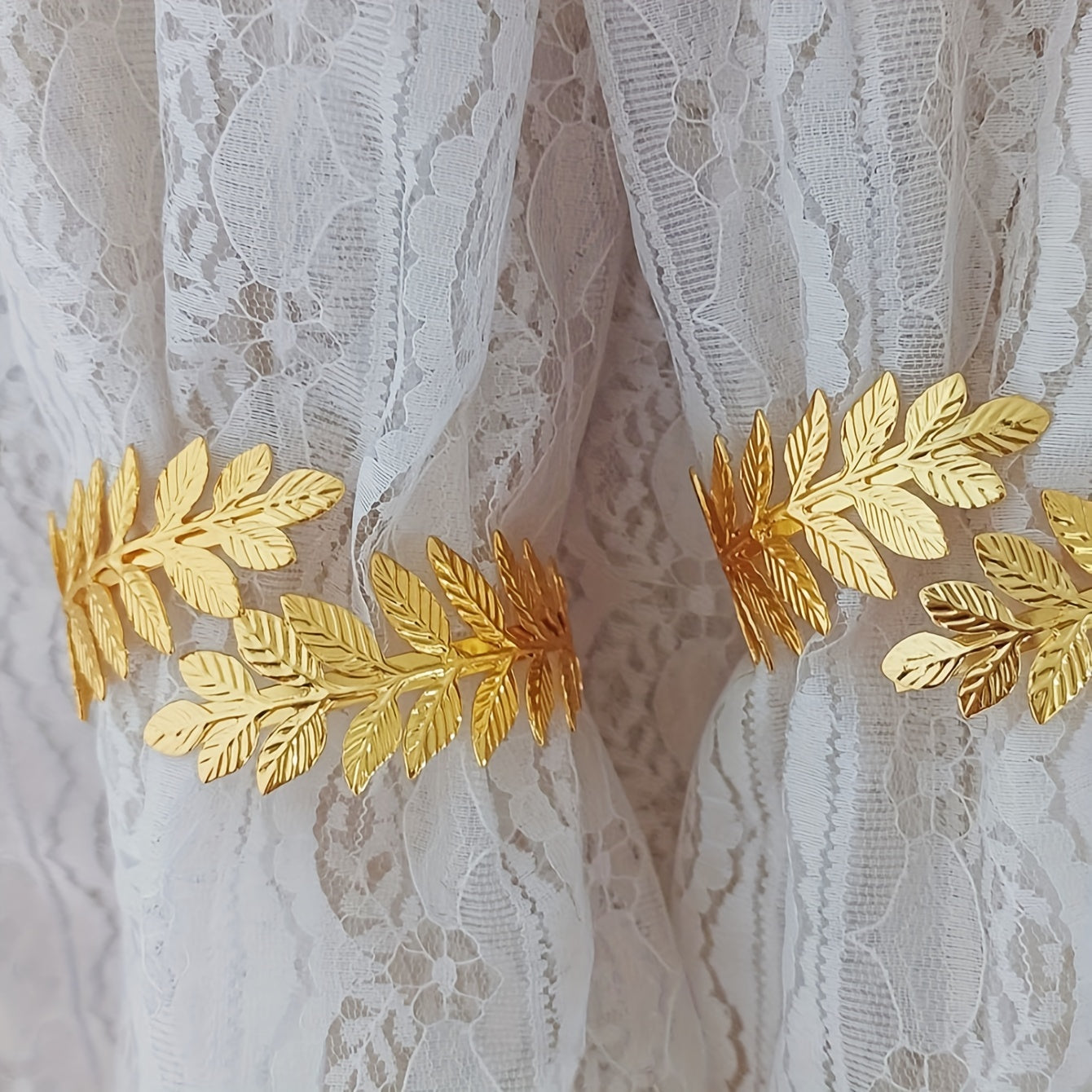 A decorative curtain tieback with gold accents, adorned with branches, leaves, and leaf-shaped hooks, perfect for enhancing home decor.