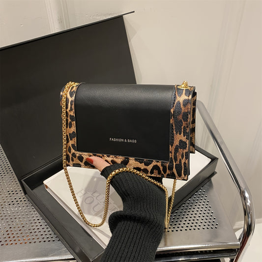 Stylish leopard print crossbody bag for women in black synthetic leather with golden-tone chain strap. Magnetic closure and large capacity, suitable for work, travel, and everyday use.