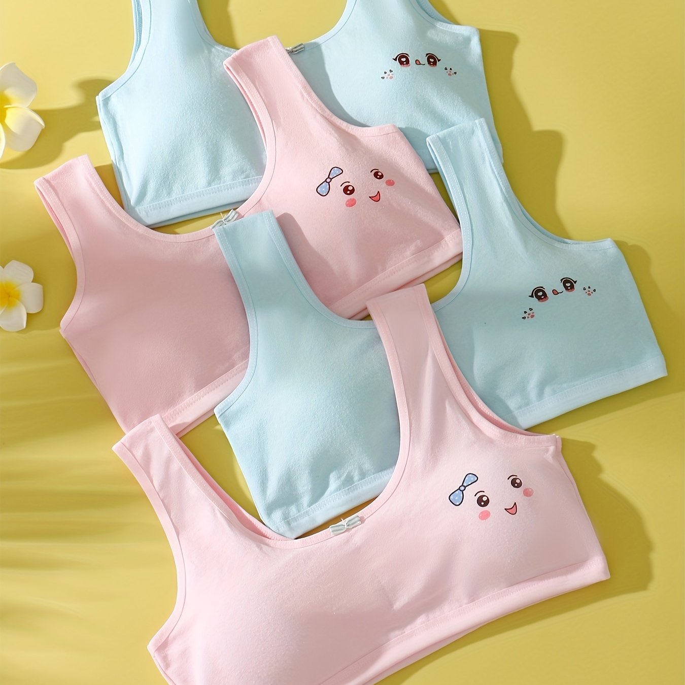 4 comfy cotton bras for girls aged 7-13 with cute animal illustrations in solid colors. Stretchy and machine washable. Includes white, yellow, blue, pink. Ideal for elementary to high