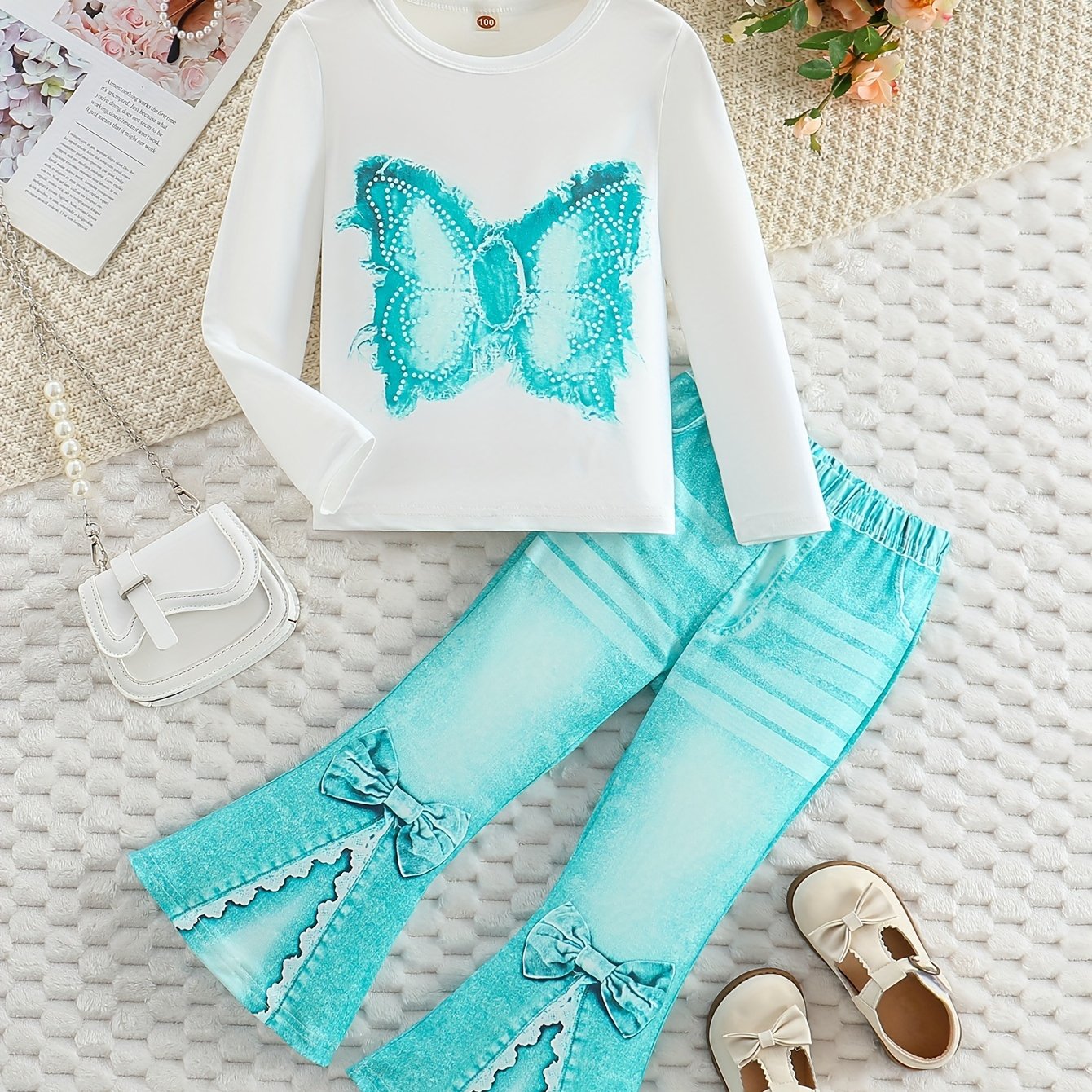 Girls' outfit set includes a long sleeve top with butterfly print and flared faux denim pants with a bow detail. Made of slight stretch knit fabric with an animal pattern, this regular fit