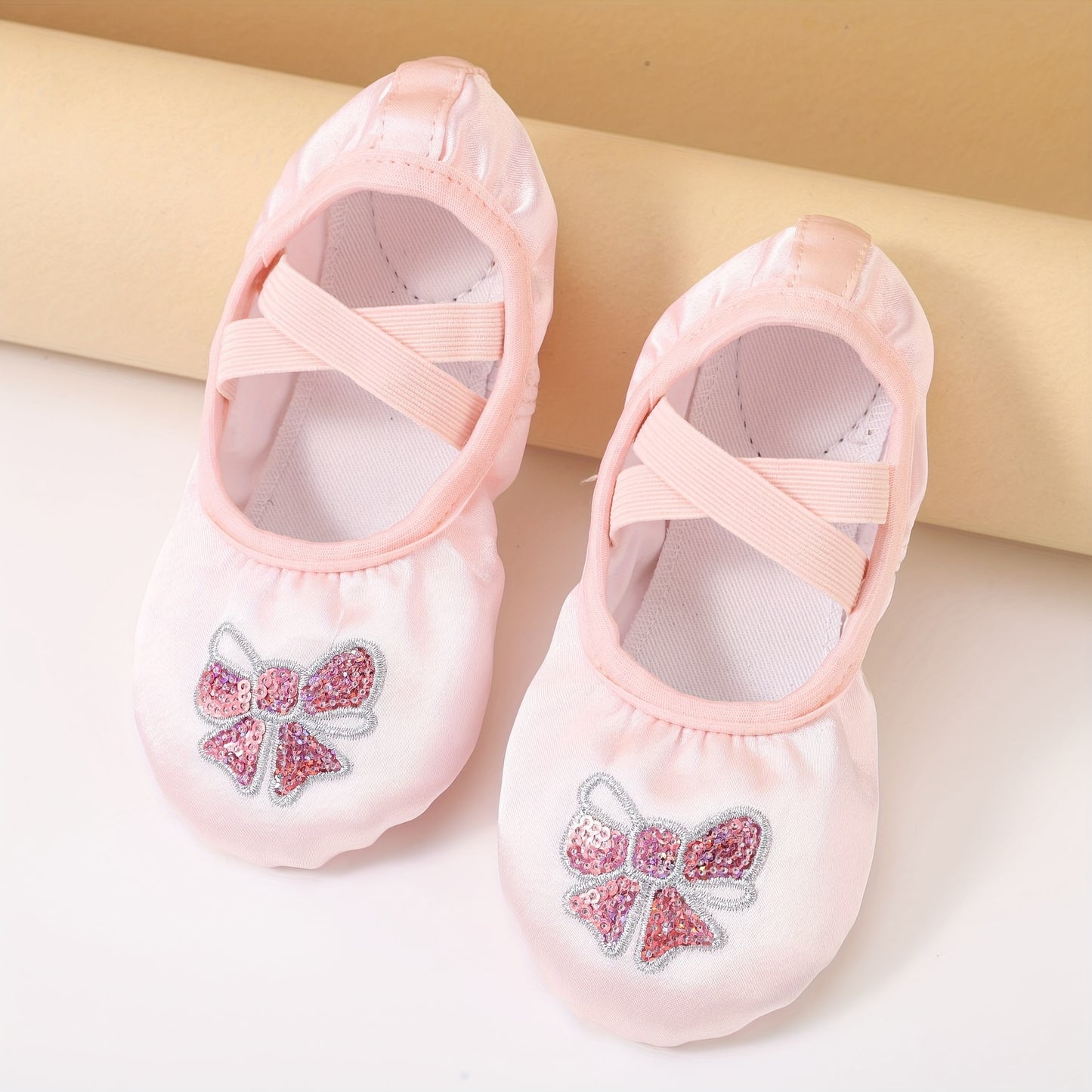 Girls’ ballet dance shoes with sparkling sequin and embroidered bow detail, soft sole, breathable canvas slip-ons. Available in pink and peach.