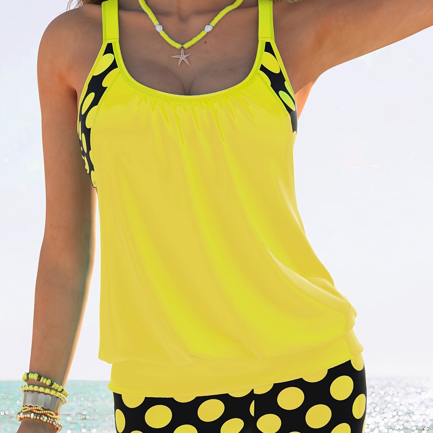 Yellow and black polka dot tankini set for women made of stretchy polyester/elastane blend. Includes round neck top with ruched design and high-waisted shorts. Machine washable. Ideal for