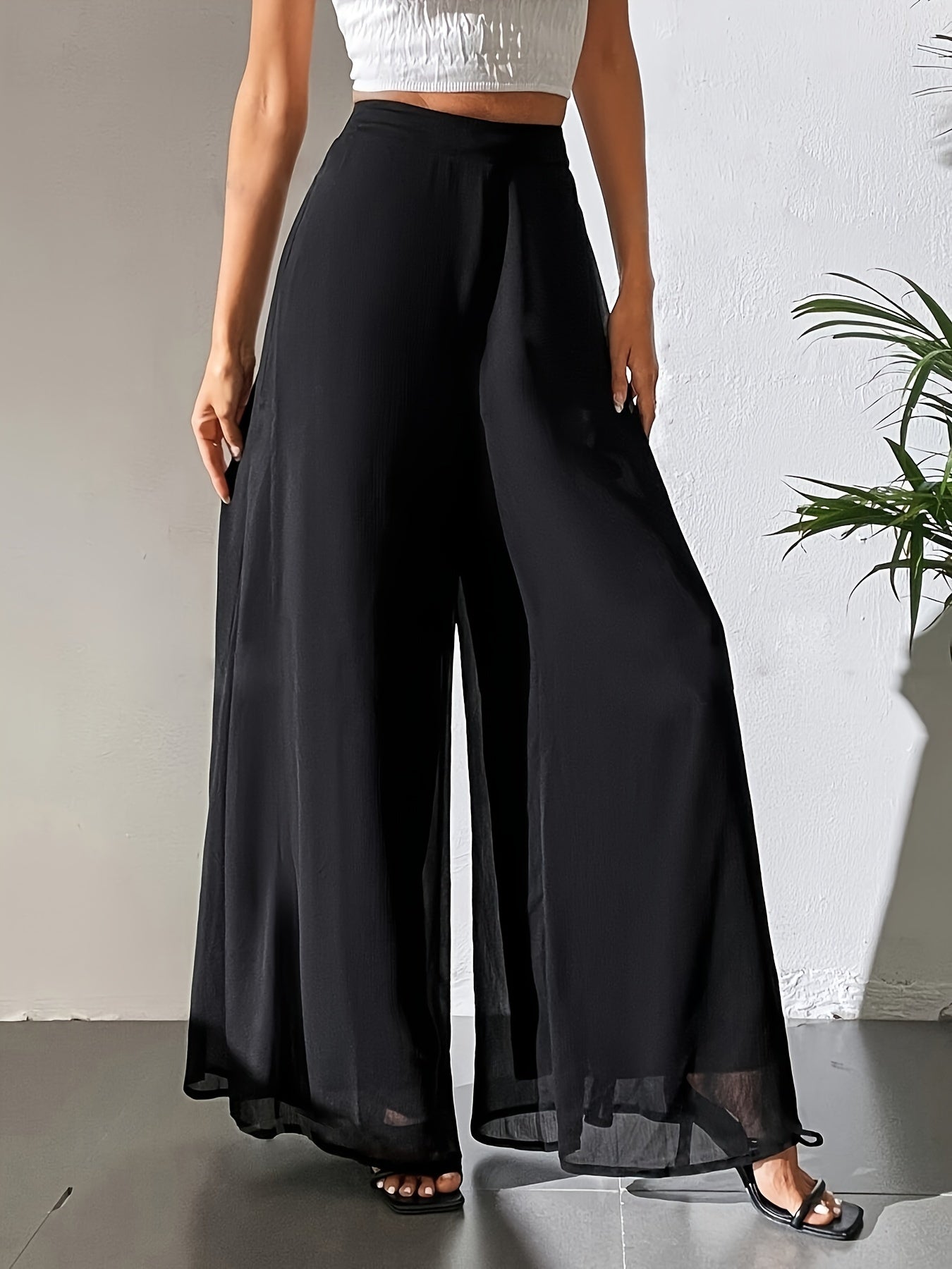 High waisted flowy black pants made of a glossy polyester/spandex blend, perfect for casual elegant attire in spring, summer, and fall.