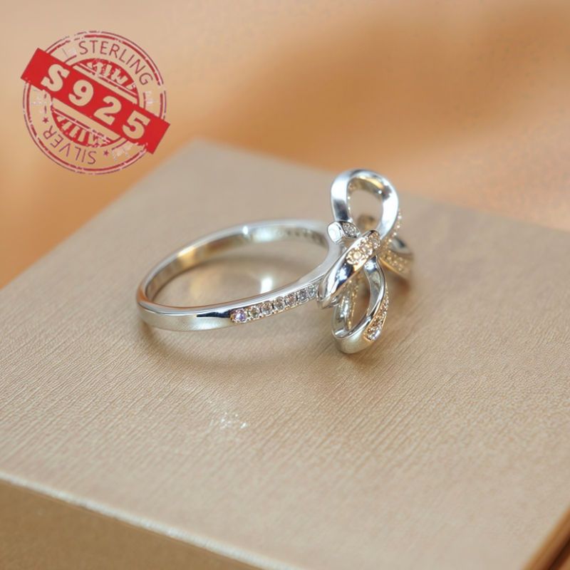 Chic 925 Sterling Silver Ribbon Bow Tie Ring featuring Natural Zirconia, perfect for July Birthdays. This Tribal & Cute style ring is 925 Silver Plated, Tarnish-Resistant, and adorned with Heart-Themed details. Ideal for Daily Wear or Wedding occasions