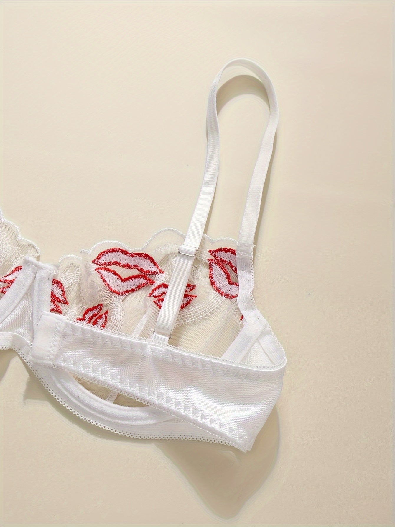 Floral embroidered lingerie set with sexy lips pattern, made of polyester knit fabric. Includes a geometric-patterned bralette and thong, no padding.