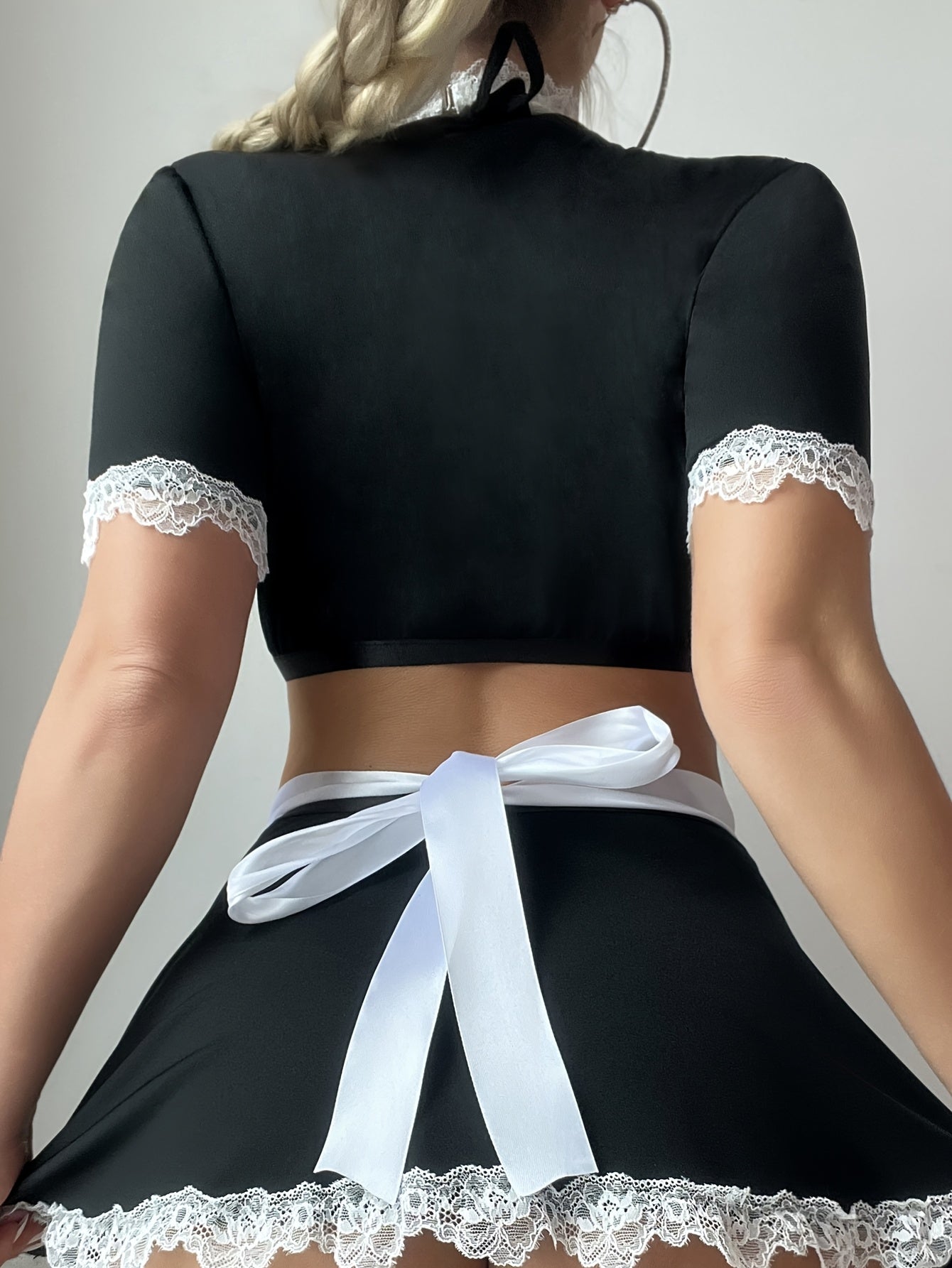 Women's sexy maid costume set includes a front button top, neck hanging bra, A-line skirt, apron, and neck ring. Made from a polyester knit fabric with elastane, contrast lace details.