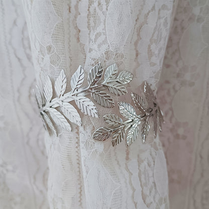 A decorative curtain tieback with gold accents, adorned with branches, leaves, and leaf-shaped hooks, perfect for enhancing home decor.