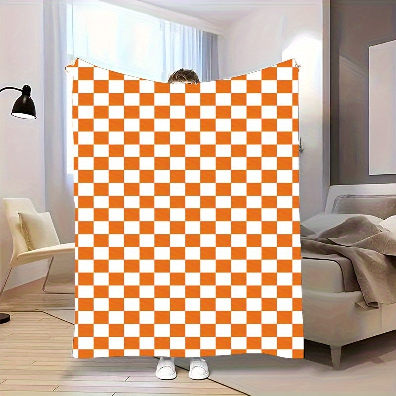 One piece of an orange and white checkered print fleece throw blanket featuring a geometric pattern. This all-season blanket is machine washable, durable, and anti-tear, making it perfect for use in the bedroom, living room, or while camping. It weighs