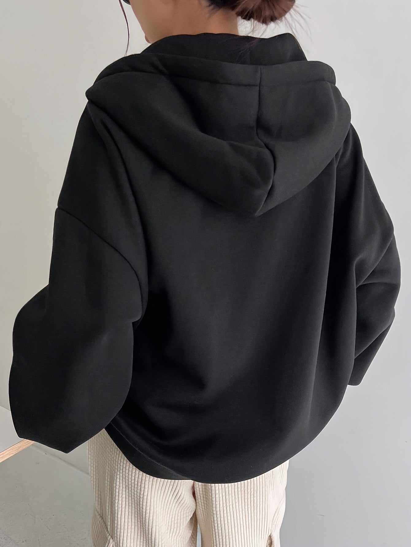 Black zip-up hoodie with fleece lining, long sleeves, loose fit, perfect for fall/winter, machine washable, features oversized hood.