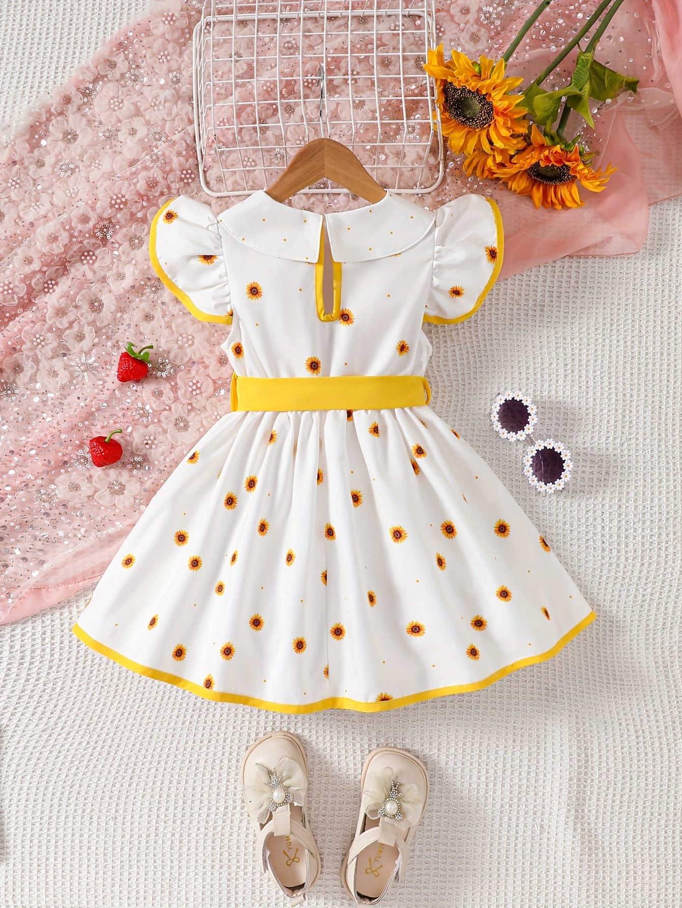 Girls' sleeveless dress with doll collar, ruffled hem, and strawberry design.