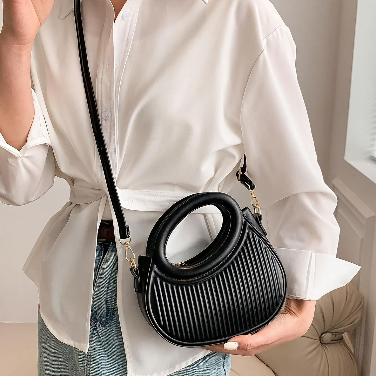 Chic black crossbody bag with embossed stripe pattern and golden-tone hardware, versatile for everyday use with a luxury look.