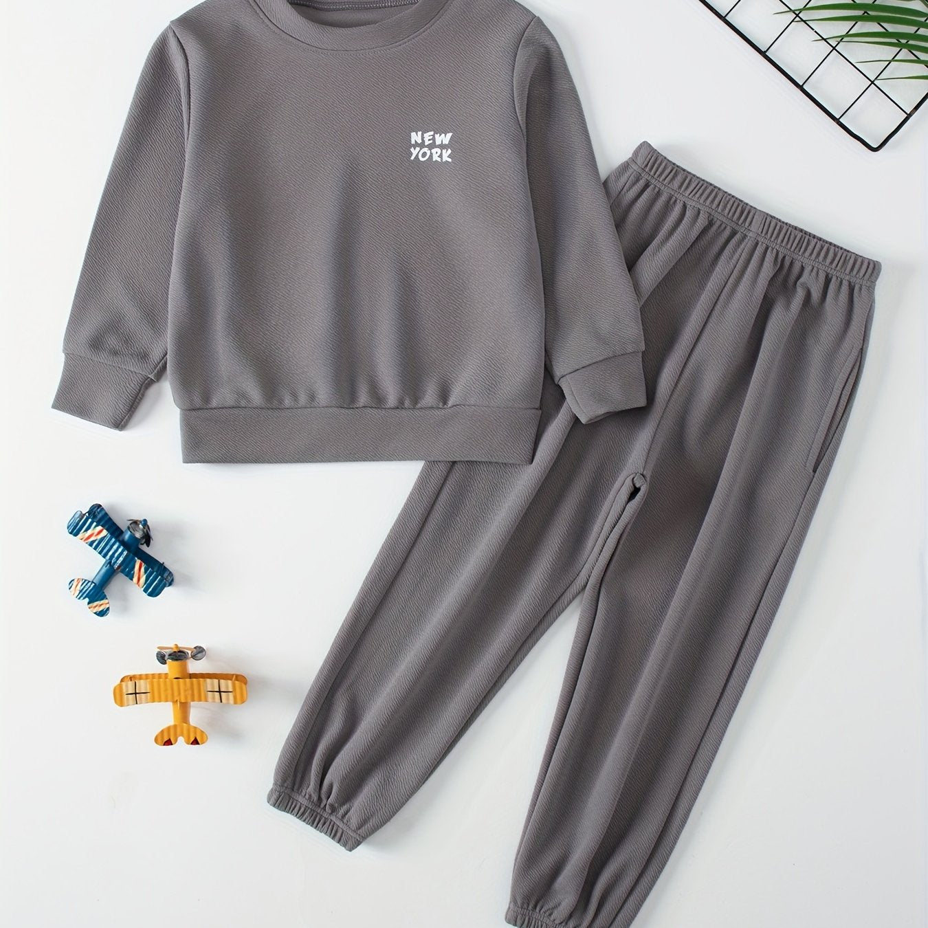 Children's casual sweatshirt and pants set made of polyester and spandex blend. Solid color with round neck, long sleeves, and knit fabric. Regular fit with pocket detail, suitable for