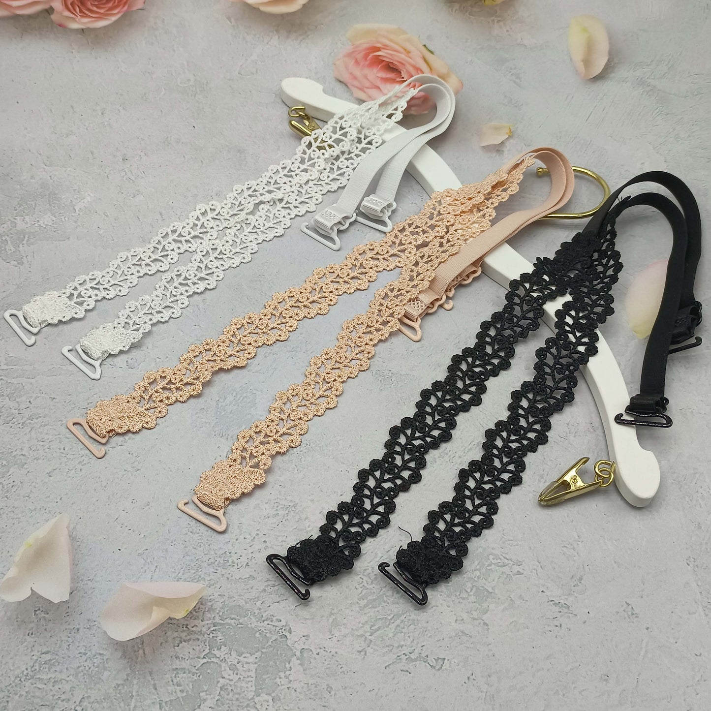 Floral bra straps in beige, white, and black with metal clasps, adjustable and made of polyester fabric; women's fashion accessory for lingerie.