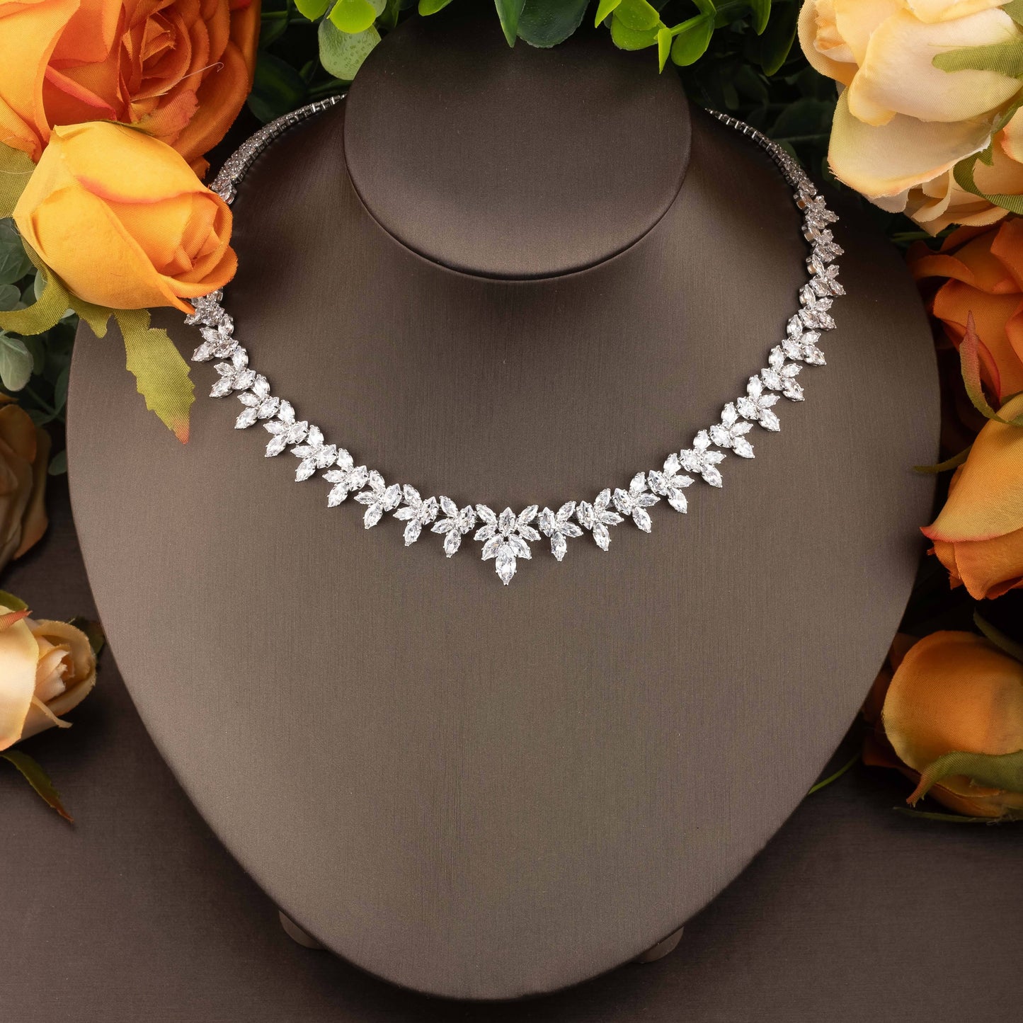 Exquisite set of jewelry adorned with cubic zirconia leaf detailing, including a necklace, earrings, ring, and bracelet, designed for women to enhance their ensemble for weddings and galas.