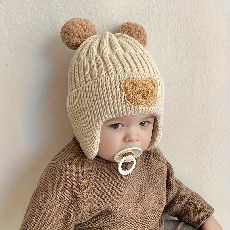 Soft polyester knit hat with cozy bear theme and ear warmers for young children, perfect winter gift for boys and girls aged 0-3 years. Comes in khaki, coffee, and ivory colors.