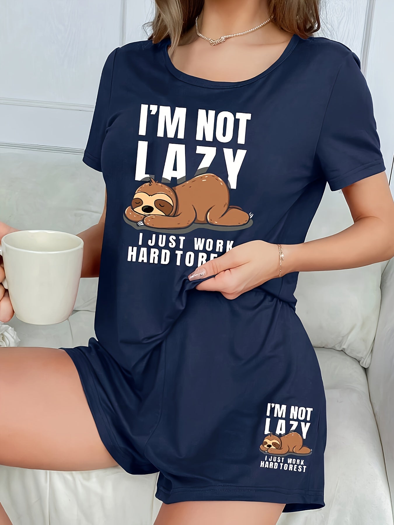 Women's sleepwear set with cute sloth print and slogan, including short sleeve top and elastic shorts.