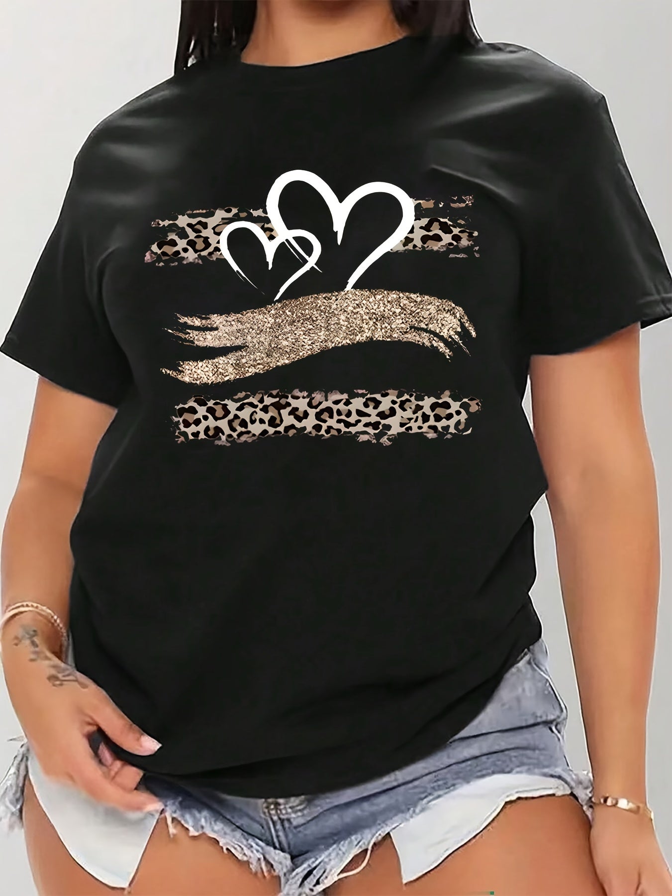 Plus size black T-shirt with leopard and heart print, made of stretchy polyester. Features a round neck, short sleeves, and is suitable for spring and summer wear.