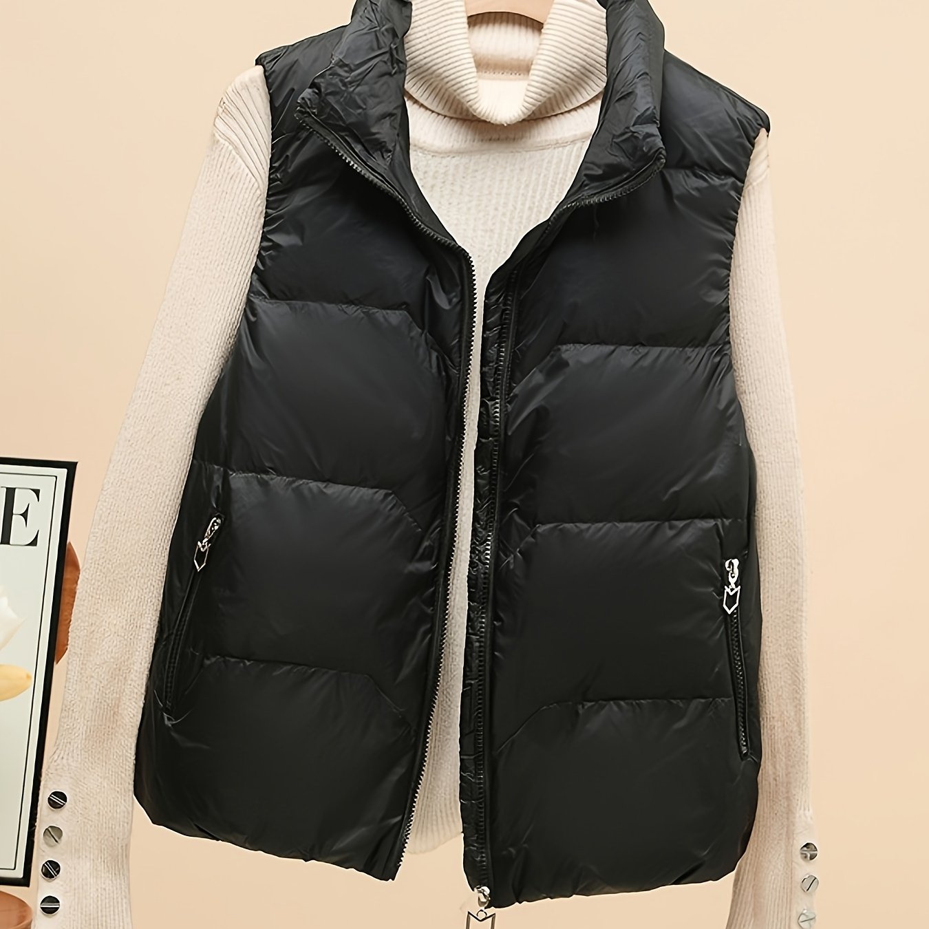 Sleeveless beige duck down vest with side pockets and zip-up closure. Perfect for fall/winter layering with a loose fit and 80g white duck down fill. Made of polyester with a glossy finish.