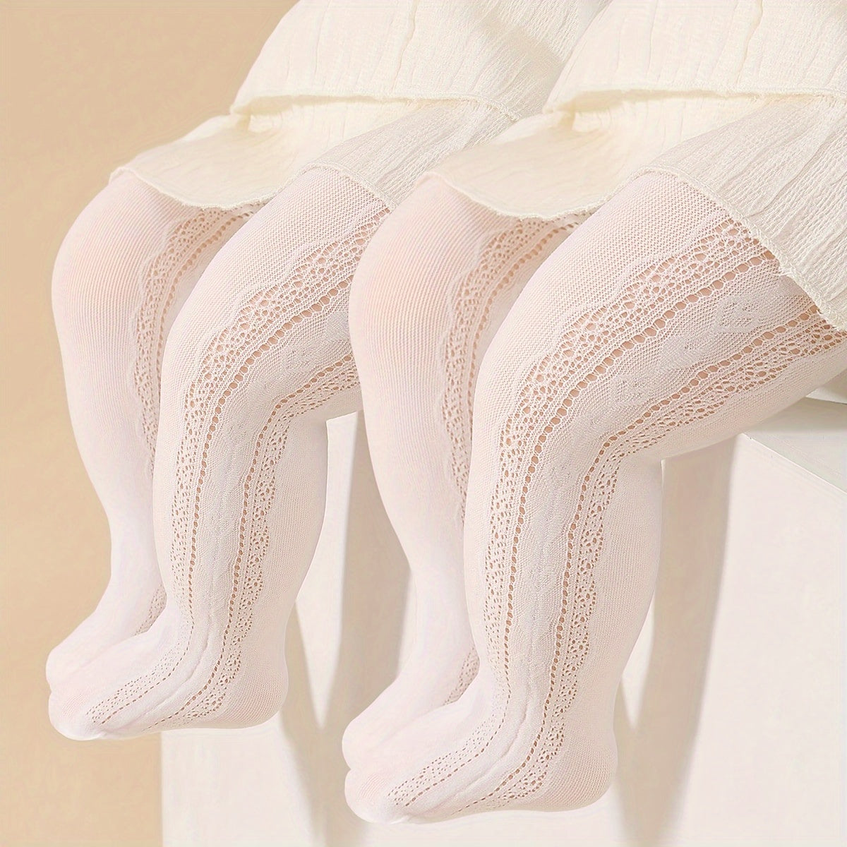 Two pairs of girls' white and beige princess-style tights with heart pattern and breathable comfort.