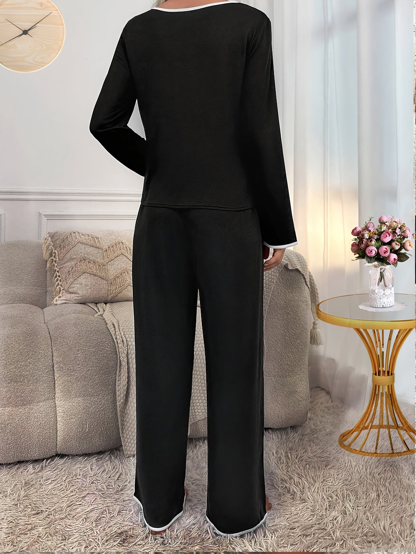 Soft polyester blend pajama set in black with white contrast trim, featuring long sleeve top and elastic waist pants with tie front for ultimate comfort and style. Perfect for cozy