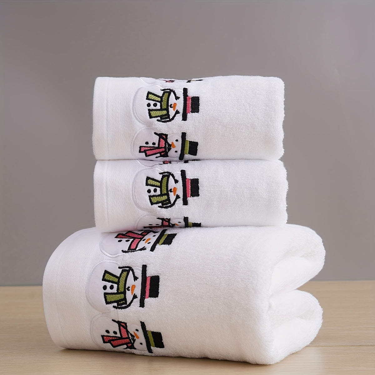 Christmas-themed towel set with embroidered snowman design. Includes 2 towels and 1 bath towel, ideal for couples' bathroom essentials and holiday gifts. Made of 100% cotton.