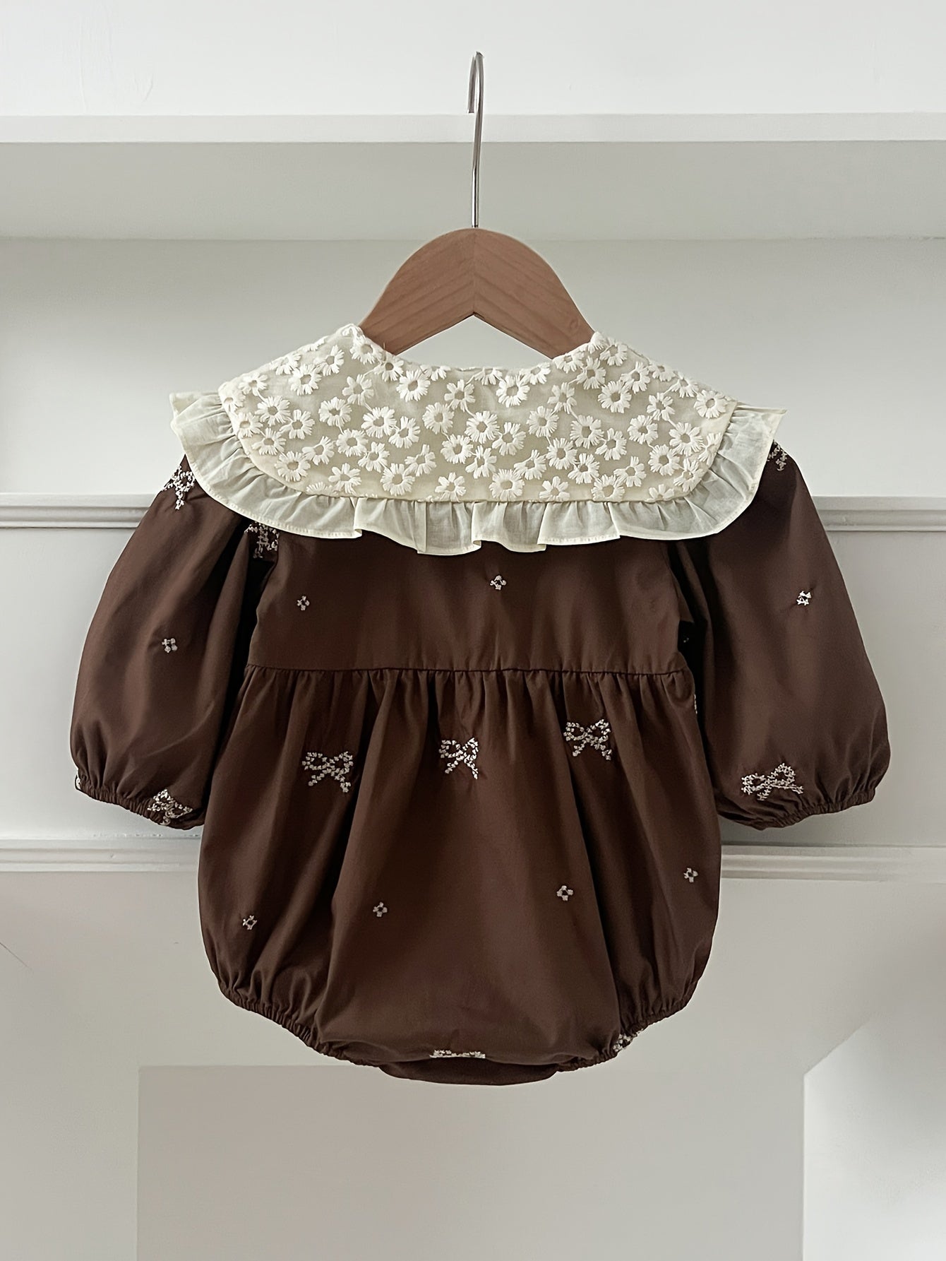 Stylish floral embroidered long-sleeve romper for baby girls, made of cotton with bow detail, ideal for spring/fall and outdoor wear.