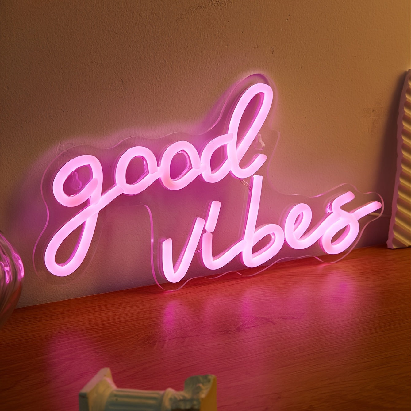 Pink cursive "Good Vibes" LED neon sign, USB powered for wall decor in bedroom, bar, or party atmosphere.